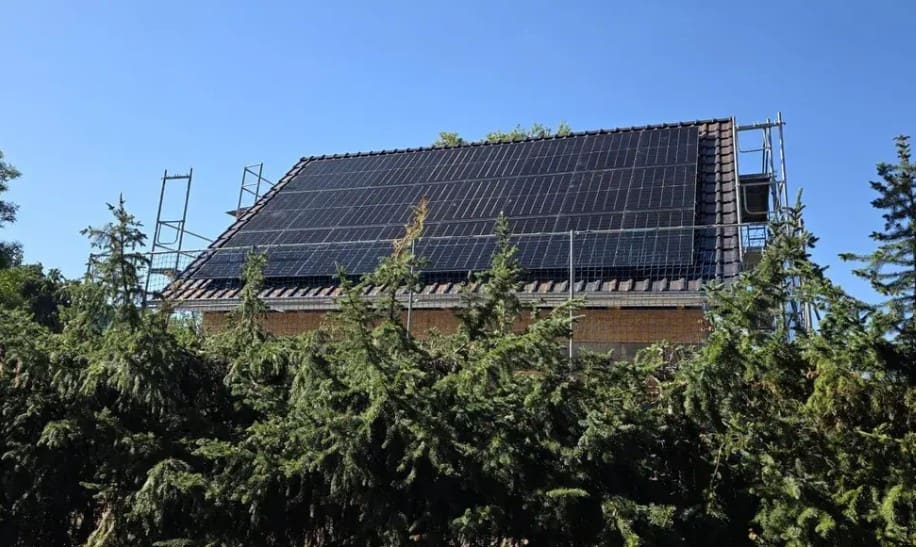 Fertig mit Photovoltaikmodulen belegtes Dach mit stehendem Gerüst