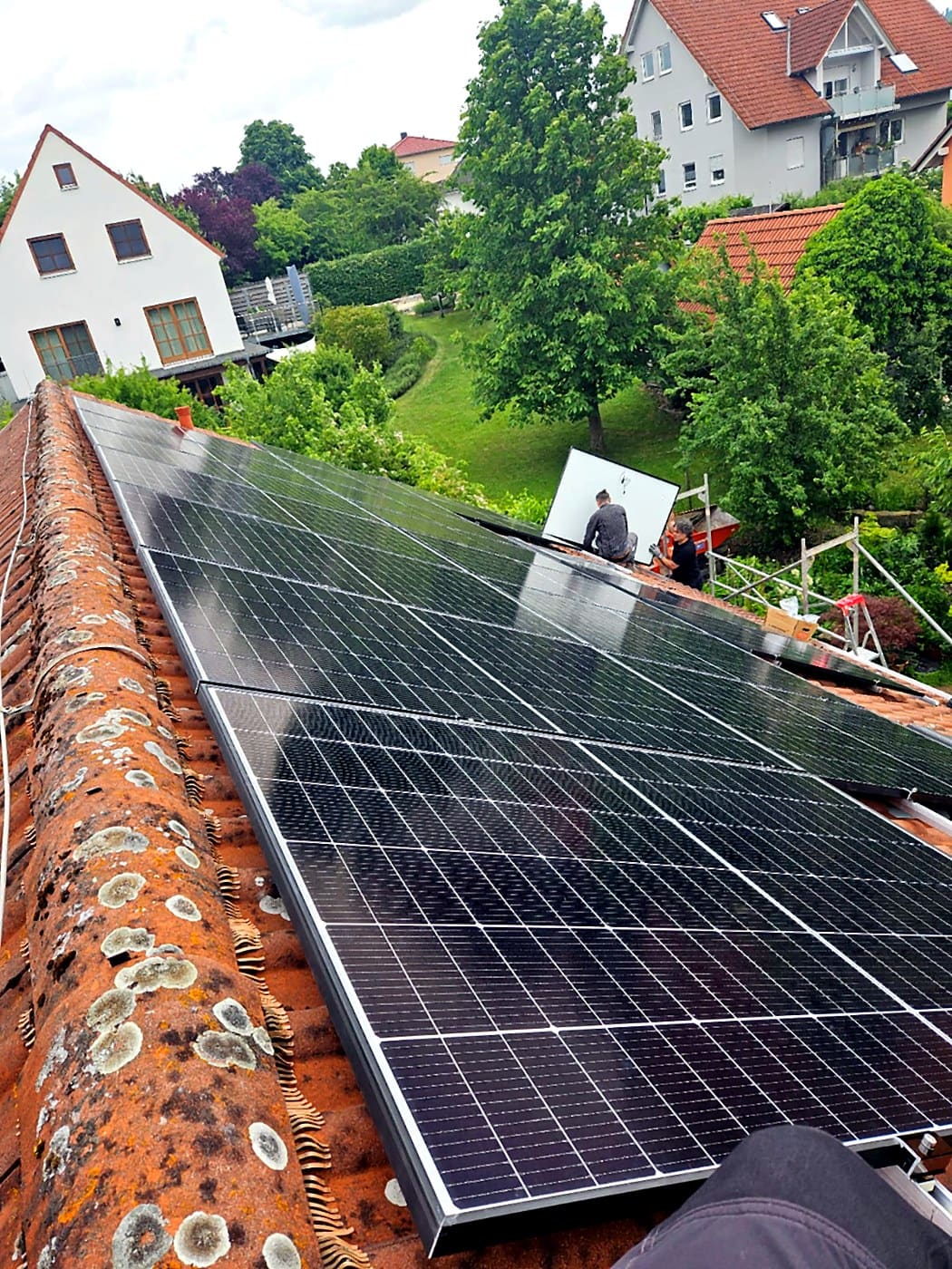 Ein Photovoltaikmodul wird auf einem Ziegeldach in das Schienensystem eingesetzt