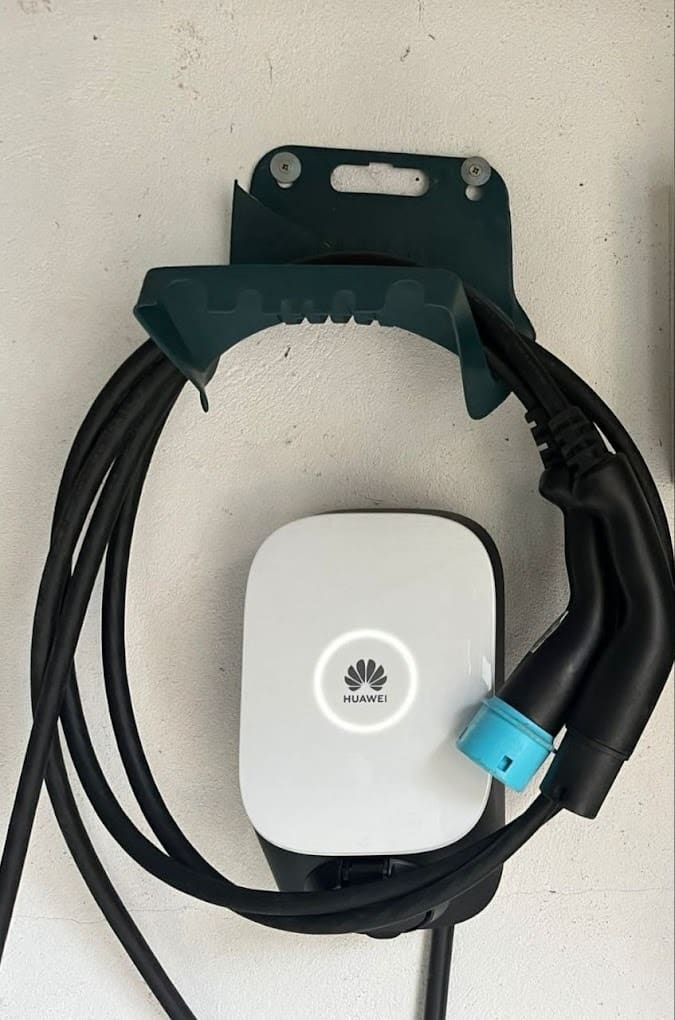 An einer Hauswand montierte Wallbox mit aufgehängtem Ladekabel